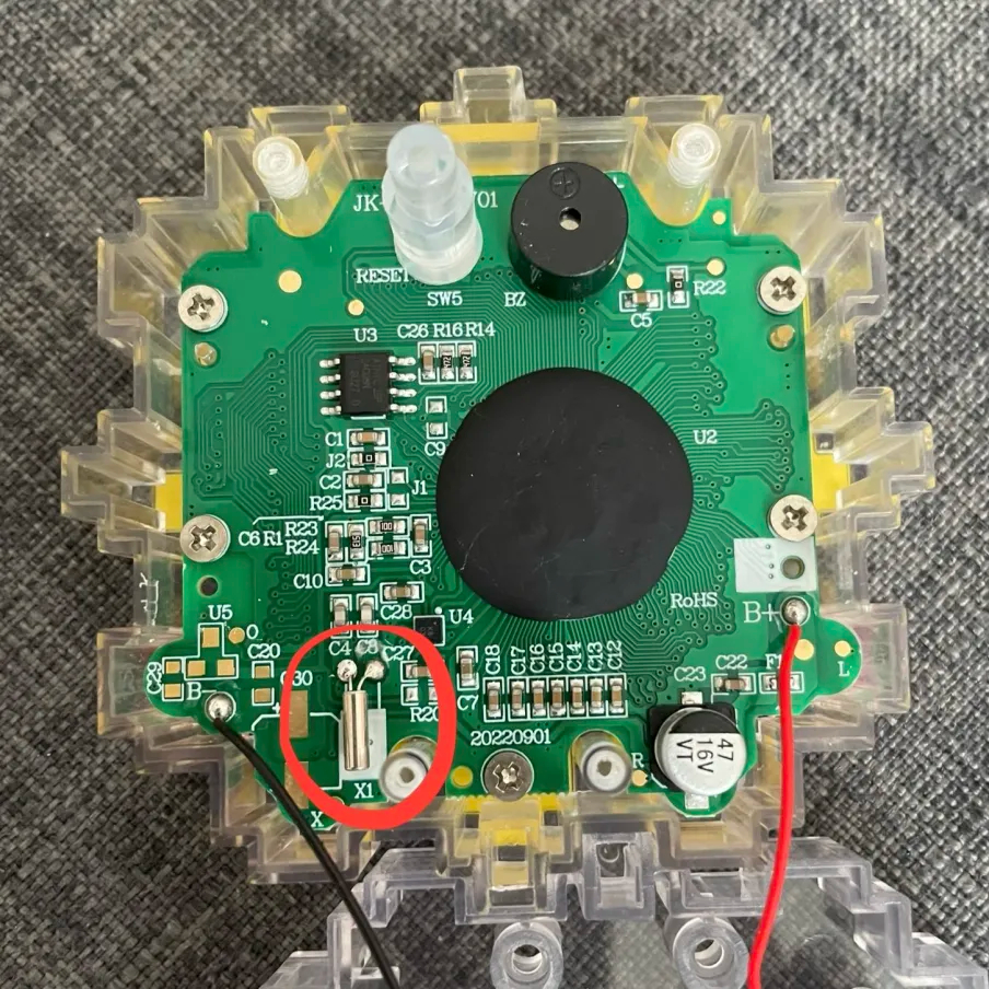 The inside of the Flower Go Walk, showing the PCB with various electronic components, including a silver cylinderical resonator circled in red.