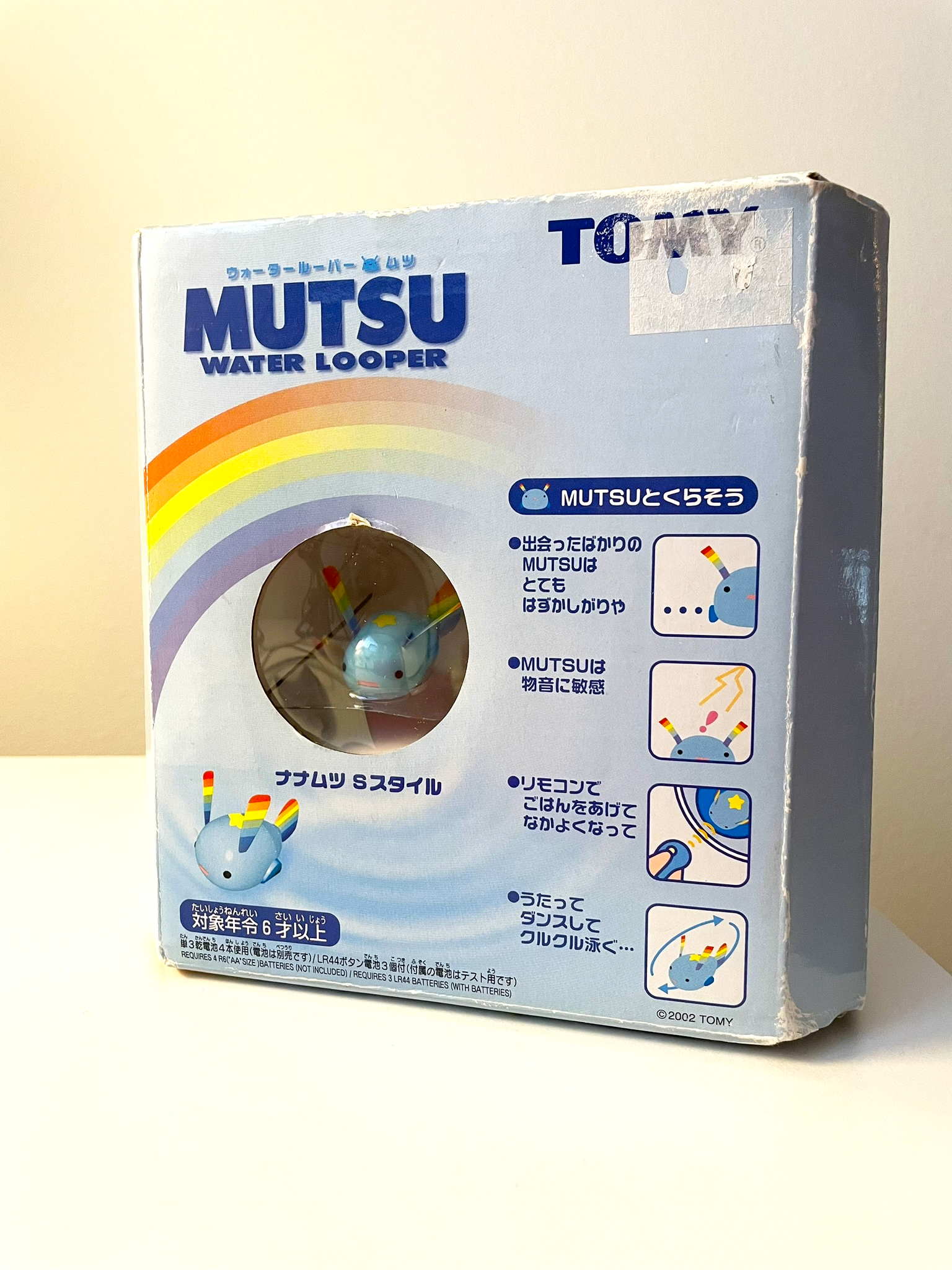 The Mutsu Water Looper box, a blue cube-shaped cardboard box with the logo, a rainbow, and some feature call-outs on the front, as well as a window where you can see Mutsu embedded in the internal plastic packaging.